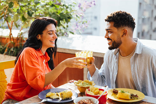 Latino couple enjoying lunch outdoors with drinks together