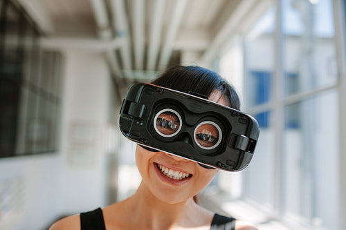 Cheerful young woman wearing virtual reality goggle