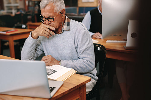 Senior man sitting in classroom and studying