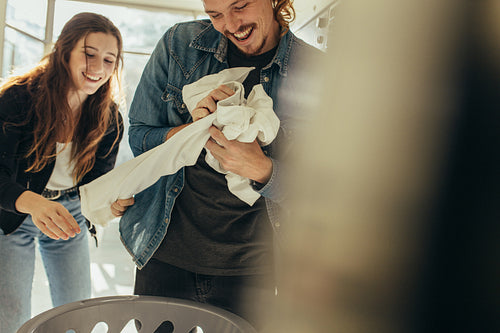 Happy couple having fun while washing clothes