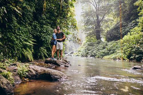 Young couple together by the creek and looking away 