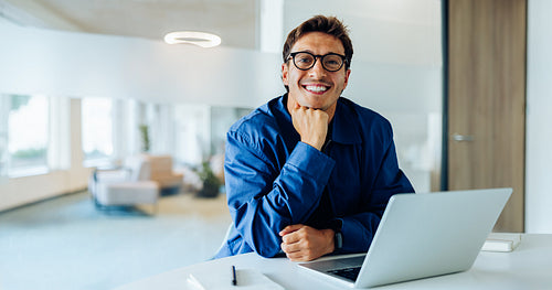Man with laptop smiling in an office