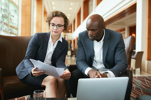 Business people discussing papers in hotel lobby