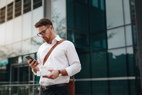 Entrepreneur standing on street checking mobile phone