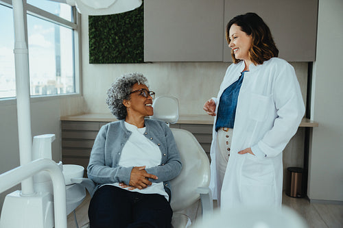 Dentist and senior patient converse pleasantly in dental clinic
