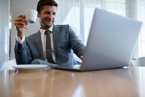 Businessman using laptop and having coffee at office