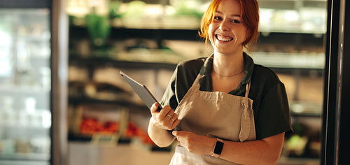 Happy shop owner smiling at the camera in her grocery store