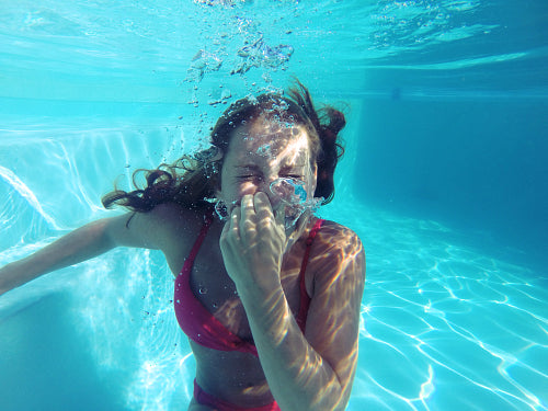 Young female holding her breath underwater