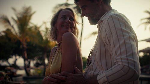 Smiling couple enjoys a romantic and affectionate moment at sunset in a tropical paradise