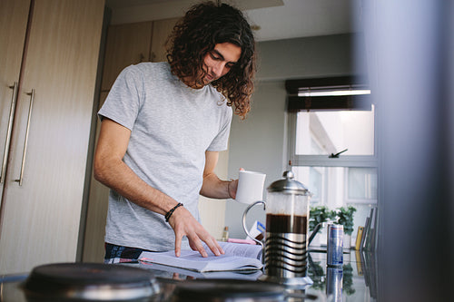 Man reading a book standing in kitchen