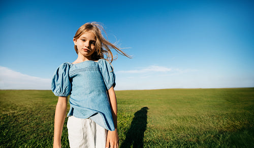 Young girl standing alone in open field enjoying freedom and nature