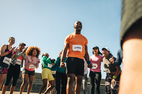 Excited male runner celebrating with cheering crowd after a race