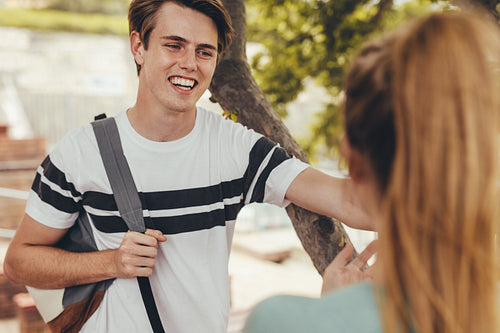 Smiling boy talking with a girl at high school campus after the class