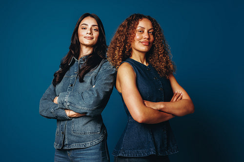 Portrait of women friends standing together with crossed arms in the studio
