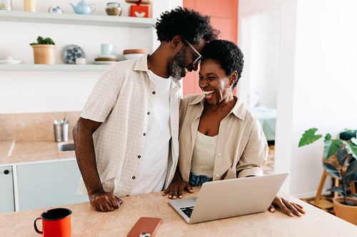 Affectionate black couple laughing and touching foreheads in the kitchen