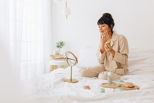 Young woman applying face cream