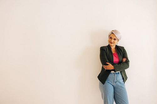 Thoughtful businesswoman standing against an office wall