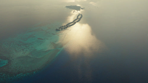 Stunning aerial drone view of a luxurious tropical island resort and turquoise ocean at sunrise