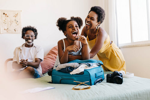 Excited black family packing travel essentials for a fun vacation