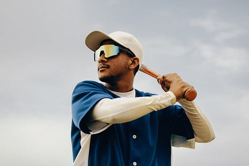 Determined baseball player in professional gear poised to swing during an outdoor game