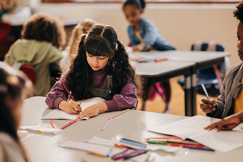 Creative young girl drawing with a pencil in a class