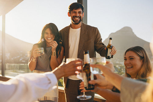 Group of friends toasting drinks together at a balcony during sunset