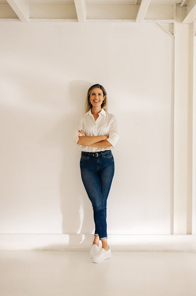 Cheerful young businesswoman standing against an office wall