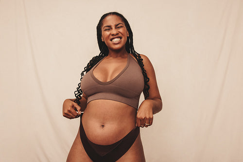 Playful young woman pulling her underwear up in a studio