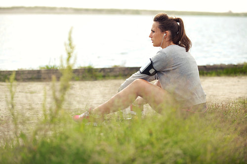 Tired Female Runner Sitting on Grass