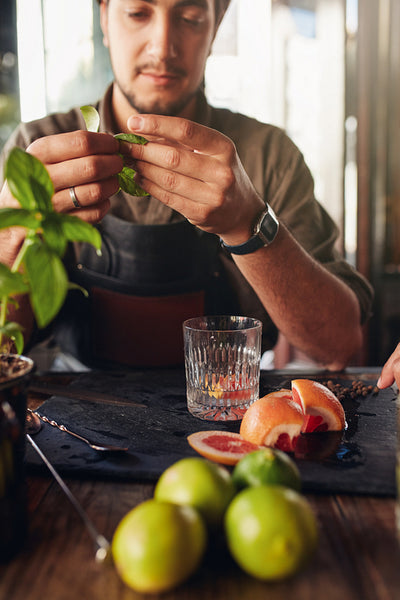 Cocktail preparation ingredients on table with bartender