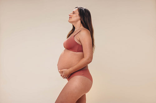 Expecting mother holding her pregnancy belly in an antenatal photoshoot