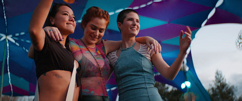 Three women dancing with drinks at a music festival