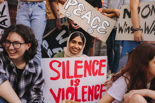 Happy Muslim girl holding an anti-violence poster