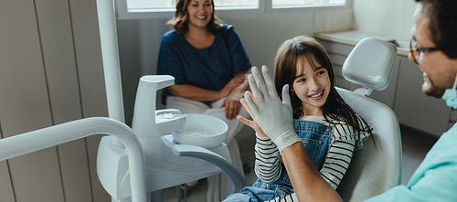 Dentist gives a high five to young patient after successful checkup