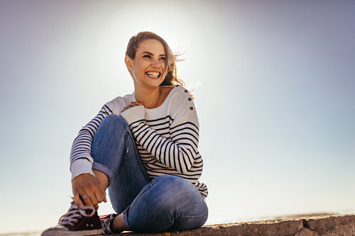 Smiling woman sitting on a sea wall