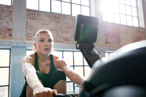 Female working out on a rowing machine at the gym