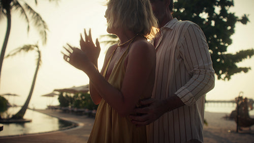 Happy couple dancing and laughing on a tropical beach at sunset