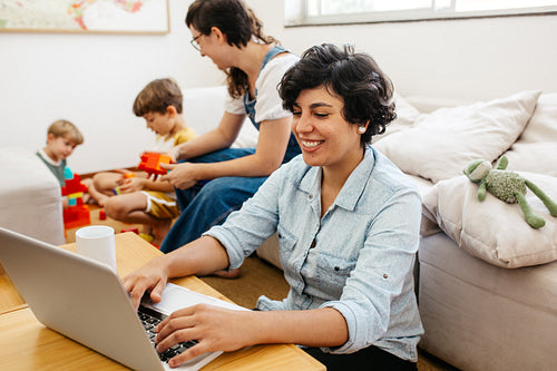 Woman working with her family playing at home