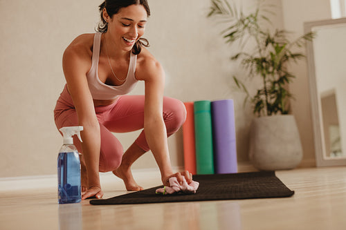 Woman disinfecting workout mat in gym