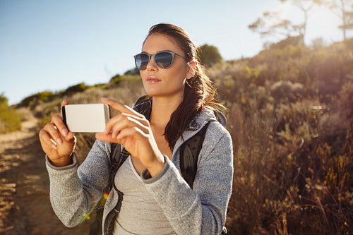 Hiker woman taking photographs with her smartphone
