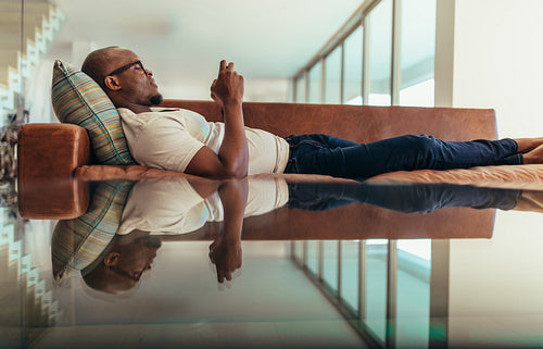 Man lying on lounge using mobile phone