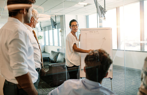 Businesswoman giving presentation to colleagues using flip board
