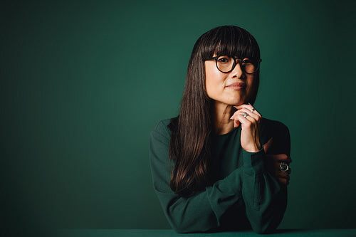 Thinking woman with glasses appears in a business portrait for the studio