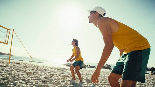 Handheld action shot of beach volleyball players playing and returning a serve