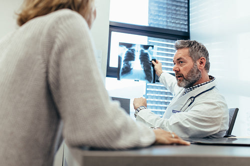 Doctor showing x-ray to his patient in medical office