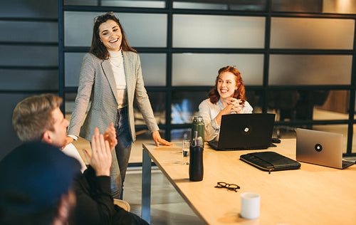 Achievement celebration: Diverse business team applauding success in creative boardroom meeting