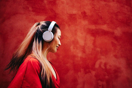 Calm woman listens to music on headphones in side profile