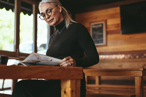 Senior woman reading a magazine at cafe