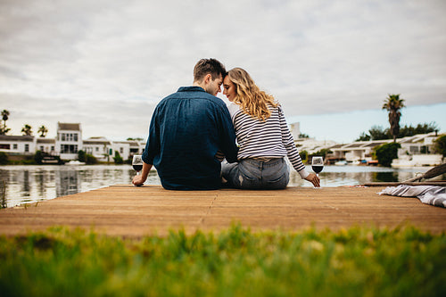 Couple sitting near a lake with drinks