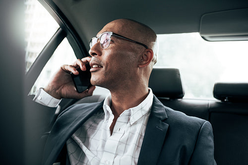 Businessman talking on mobile phone sitting in car